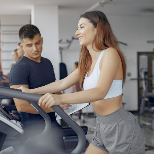 Young sports people training in a morning gym Handsome man in a gym. Sportspeople in a sportswear. Woman training with coach